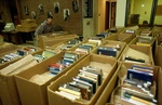 Movers organize boxes of books. by Marc Featherly